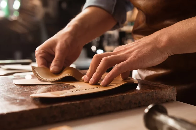 Artisan fabriquant un collier en biothane sur un établi, mettant en avant le travail manuel du cuir et des matériaux résistants.