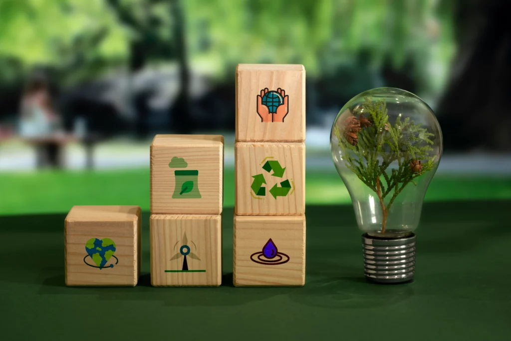 Symboles de recyclage et d’énergie verte sur des cubes en bois, avec une ampoule contenant une plante.
